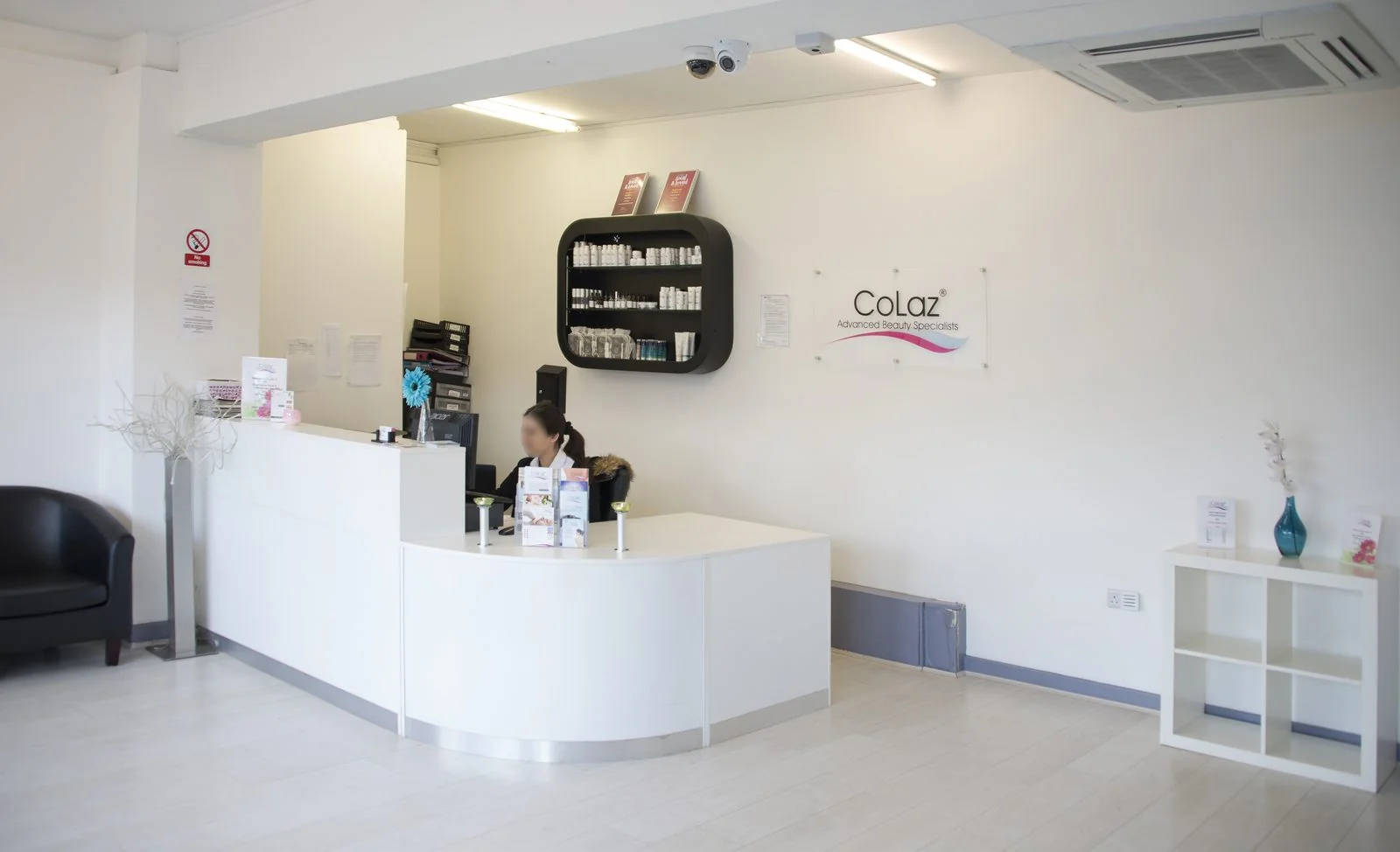 Bright reception area at the CoLaz Hounslow clinic with the curved white front desk and brand sign on the wall
