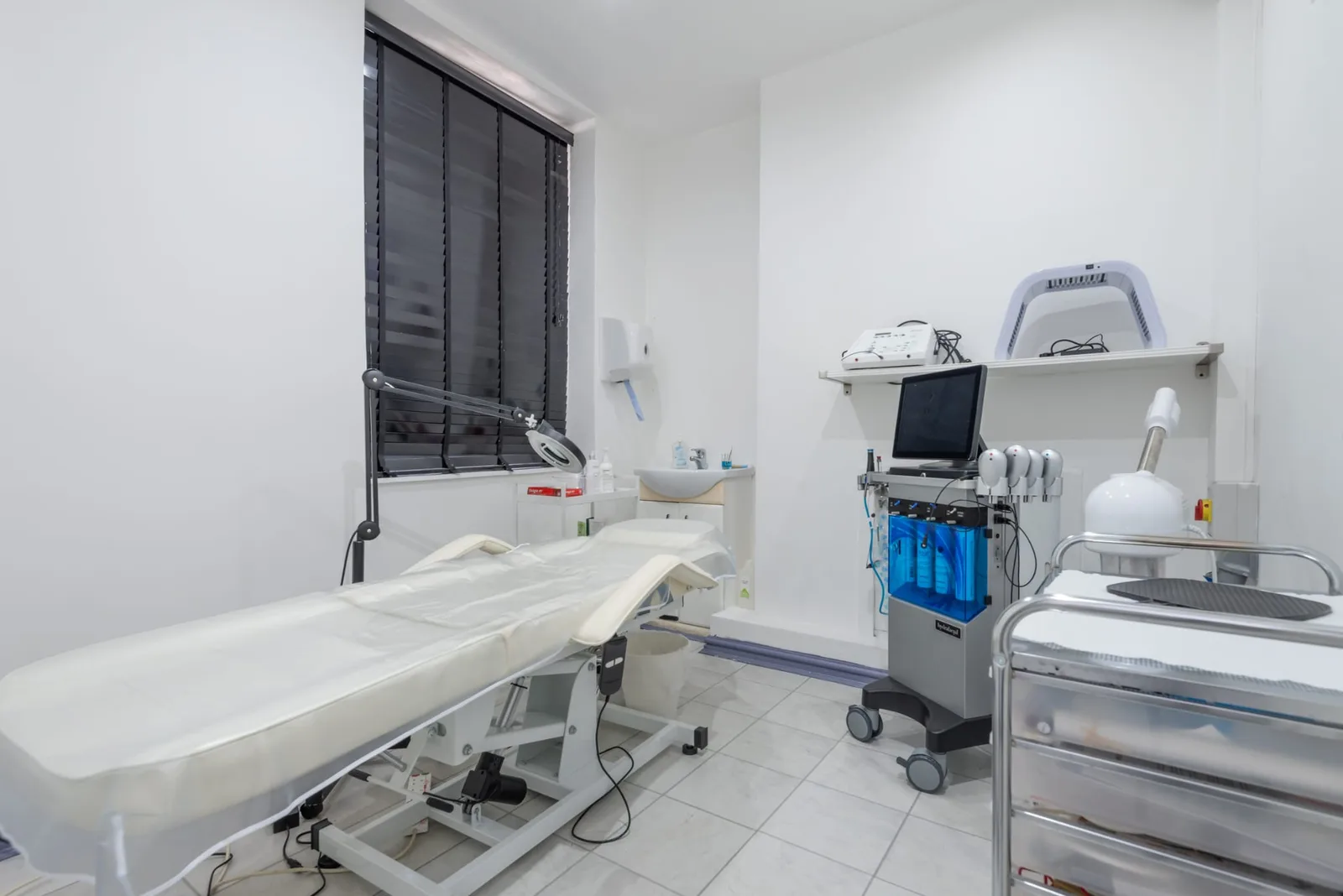 Private treatment room at the CoLaz London Paddington clinic with a treatment bed beside the window and a Hydrafacial machine and facial steamer alongside