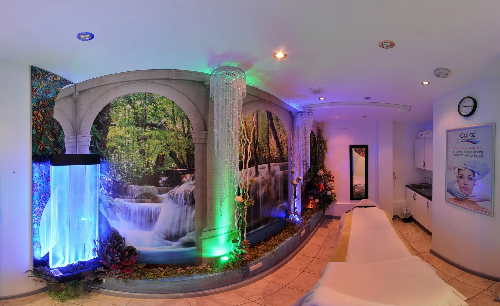 Spa-themed treatment room at the CoLaz Slough clinic with a waterfall mural, illuminated water-column feature and treatment bed