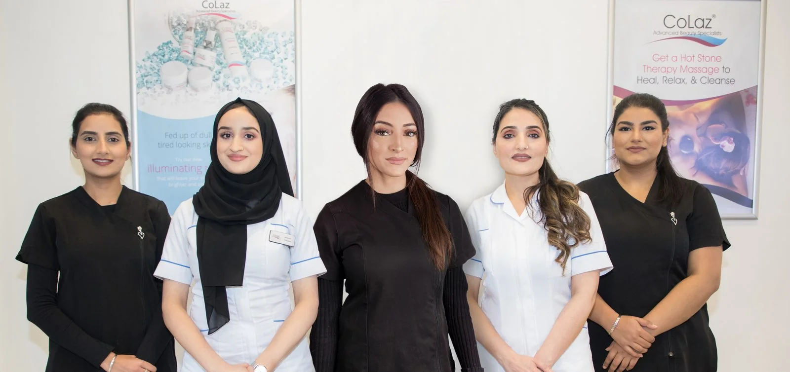Five qualified clinicians of the CoLaz Slough team in branded uniform standing in front of the clinic posters