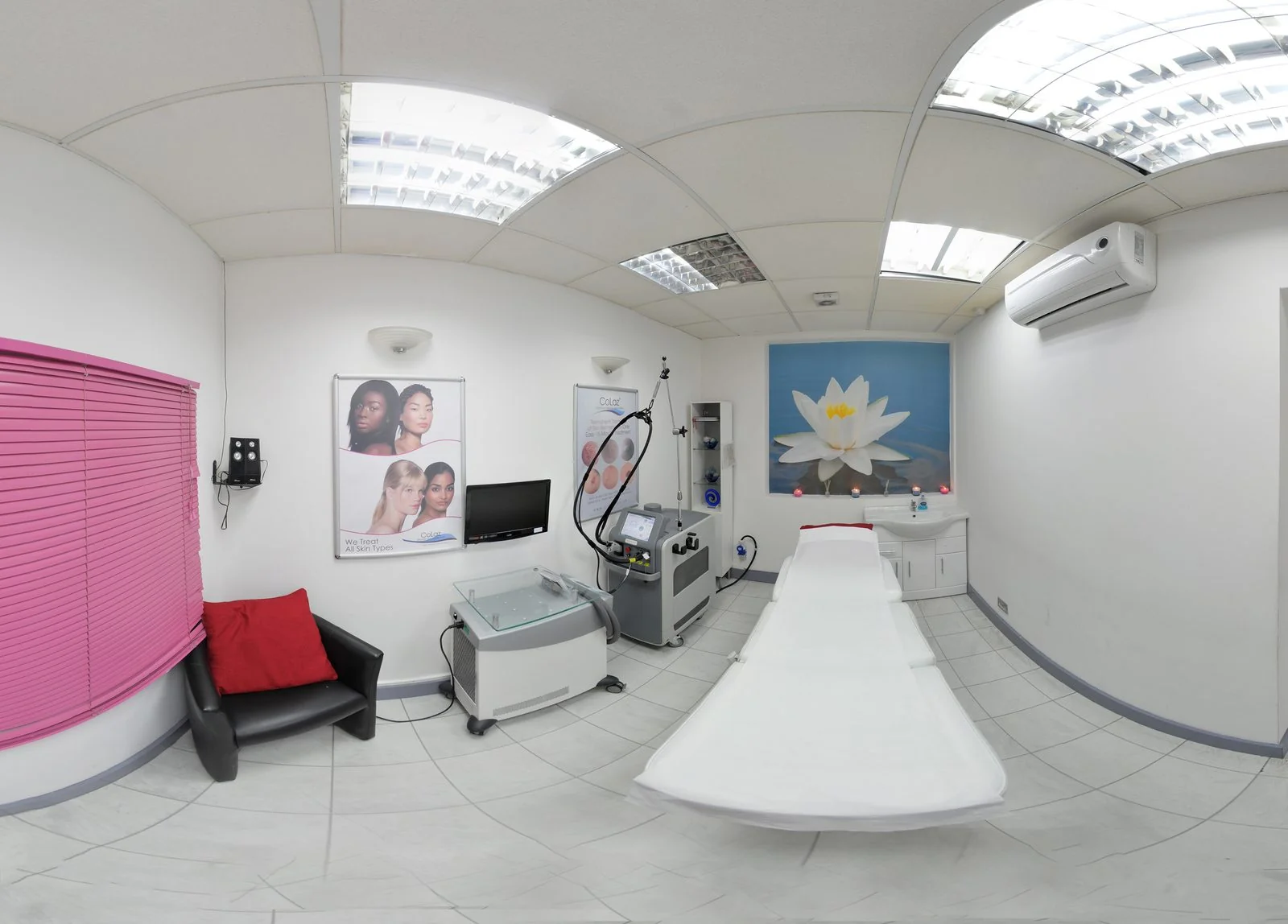 Bright laser treatment room at the CoLaz Southall clinic with pink window blinds, a lotus mural and the laser device beside the bed