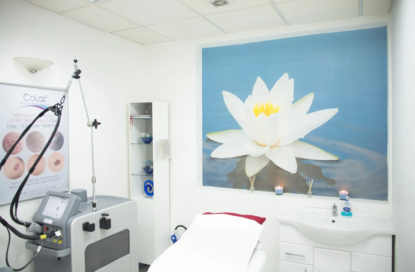 Treatment room at the CoLaz Southall clinic with a calming lotus flower mural above the bed and clinical equipment to the side