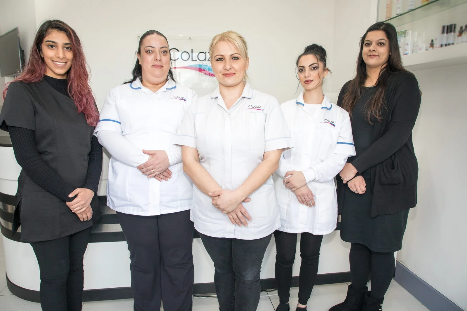 Five qualified clinicians of the CoLaz Wembley team in branded uniform standing in front of the clinic reception