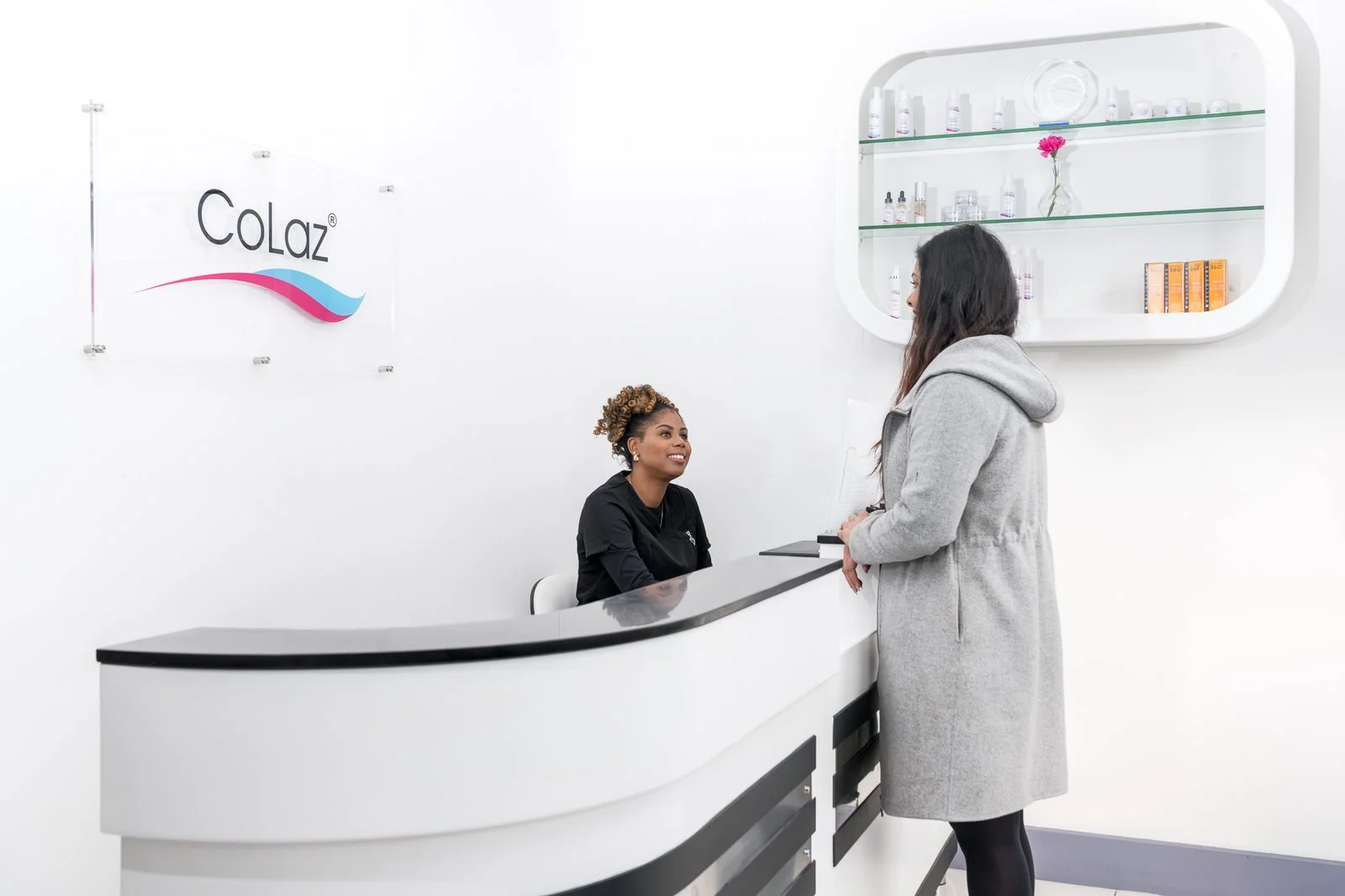 Patient at the CoLaz Wembley clinic reception booking her next non-surgical Brazilian bum lift session at the front desk