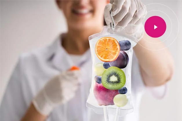 Conceptual image of an IV bag filled with whole fresh fruit held by a clinician, illustrating the vitamin and antioxidant blends delivered through CoLaz IV vitamin therapy