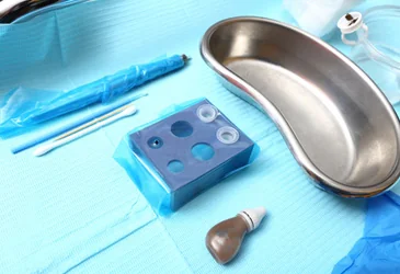 Sterile microblading station laid out at a CoLaz clinic with the fine blade, pigment cups, custom pigment mix and kidney dish on a clean blue clinical drape