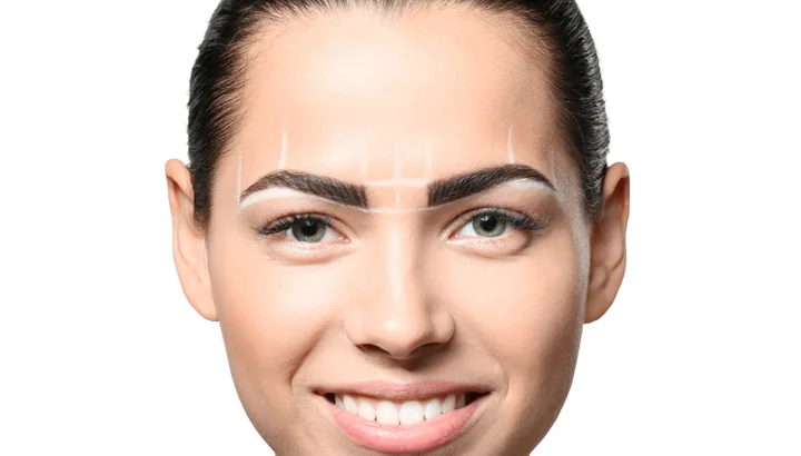 Client with the symmetrical brow-shape mapping lines drawn in white pencil across both eyebrows before the microblading session begins at CoLaz